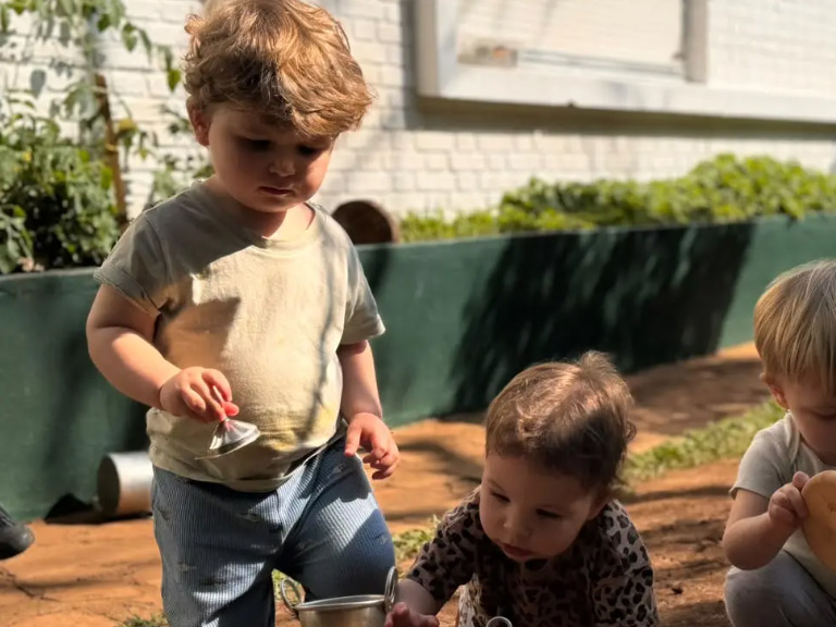 Bebê brincando com tinta no jardim