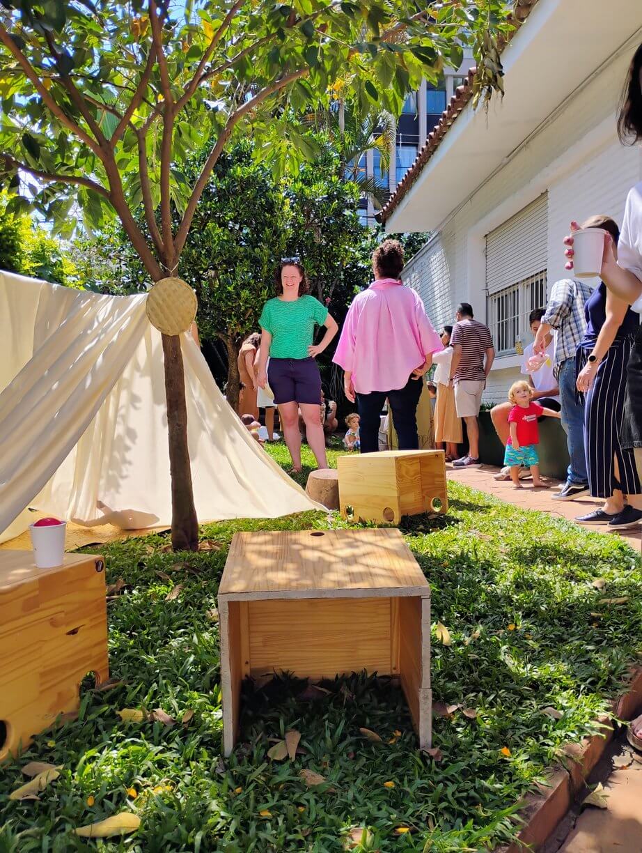 Famílias chegando ao jardim da escola, com uma cabana de tecido