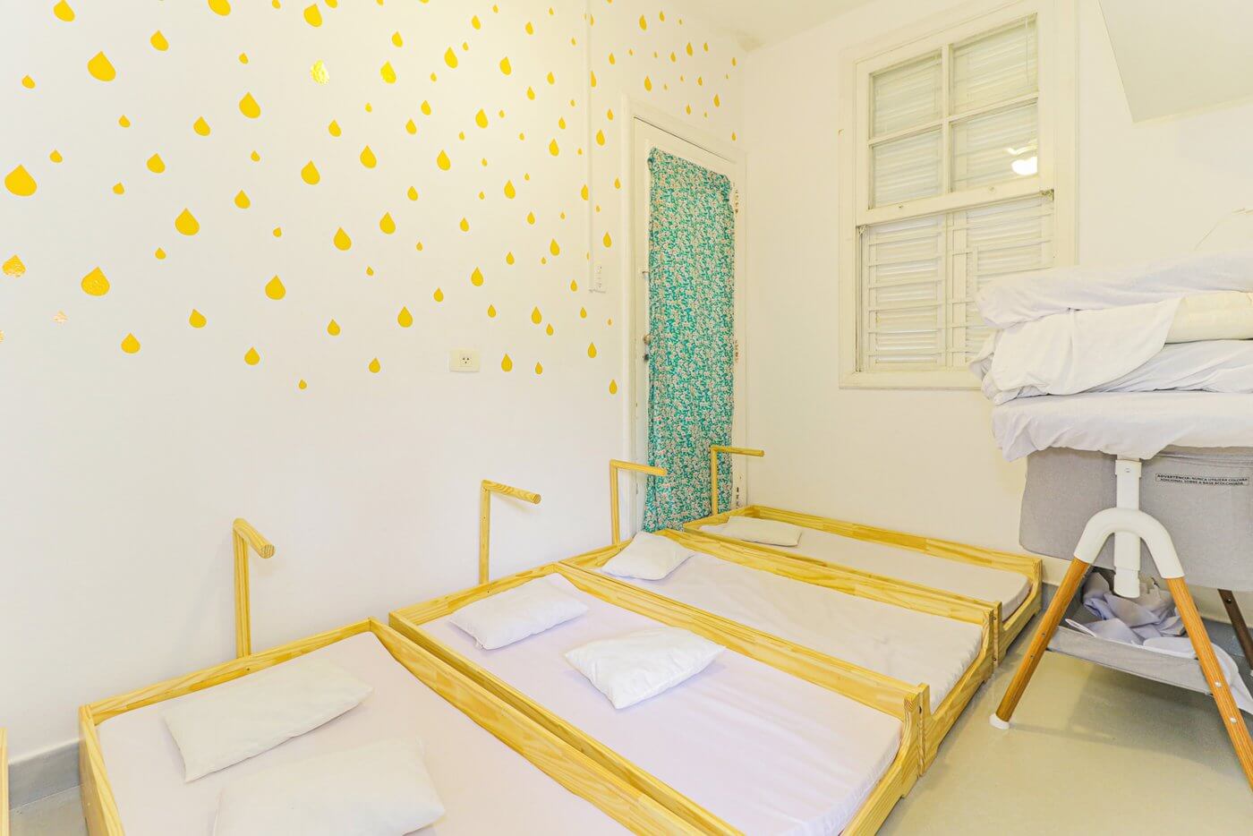 Sala de sono com colchonetes baixos e gotas amarelas na parede